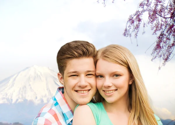 Sonriente pareja abrazándose sobre montañas fondo —  Fotos de Stock