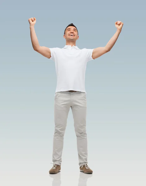 Щасливий чоловік з піднятими руками на сірому фоні — стокове фото
