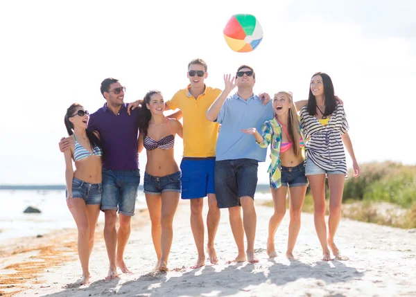 Group of happy friends walking along beach — Stock Photo, Image