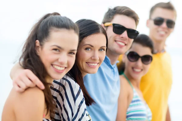 Groep gelukkige vrienden knuffelen op strand — Stockfoto