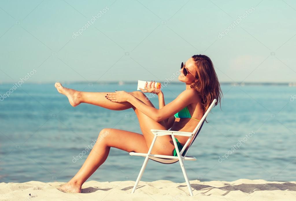 Smiling young woman sunbathing in lounge on beach Stock Photo by  ©Syda_Productions 68955509