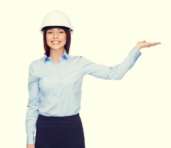 Businesswoman in helmet holding something on palm — Stock Photo, Image