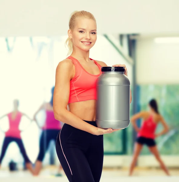 Smiling sporty woman with jar of protein — Stock Photo, Image