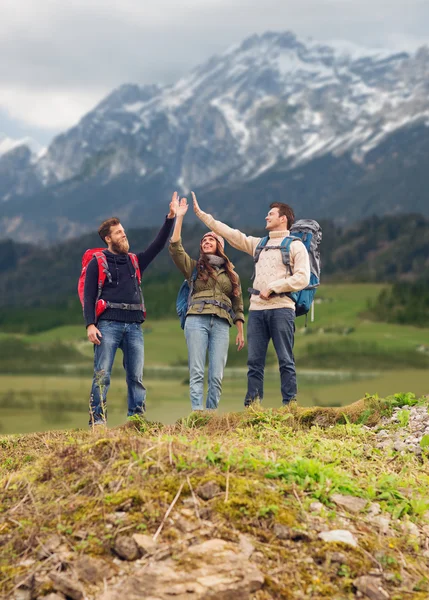 Groep lachende vrienden met rugzakken wandelen — Stockfoto