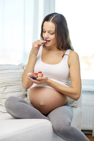 Happy pregnant woman eating fruits at home — Stock Photo, Image
