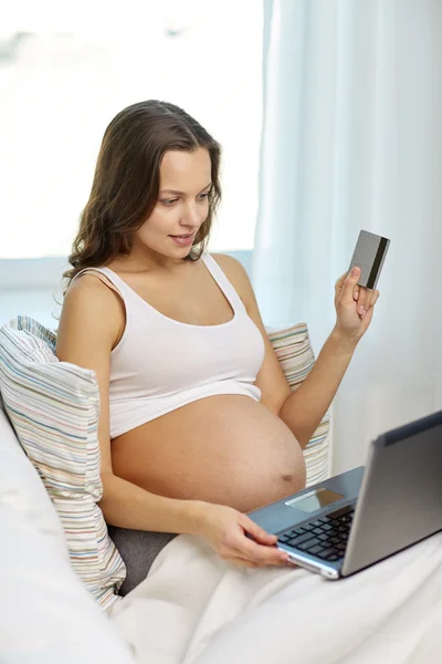 Femme enceinte avec ordinateur portable et carte de crédit à la maison — Photo