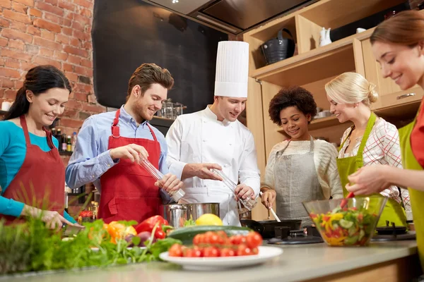 Happy friends and chef cook cooking in kitchen — Stock Photo, Image