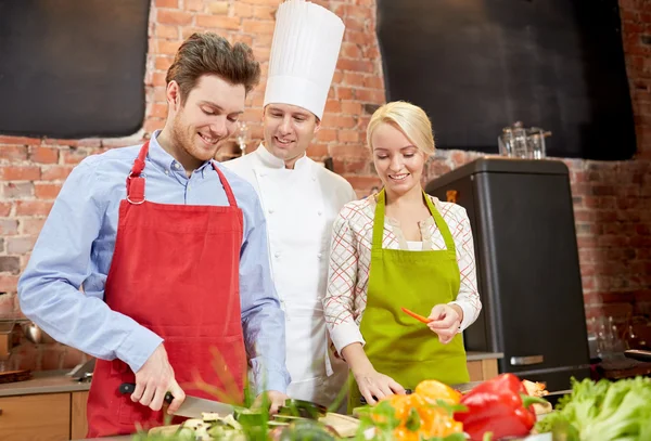 Gelukkige paar en mannelijke chef kok koken in de keuken — Stockfoto