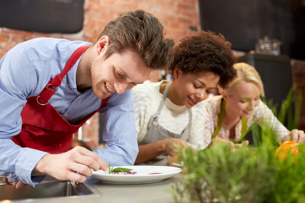 Amigos felices cocinar y decorar platos —  Fotos de Stock