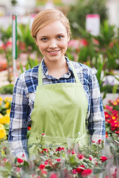 Glad kvinna med blommor i växthus — Stockfoto