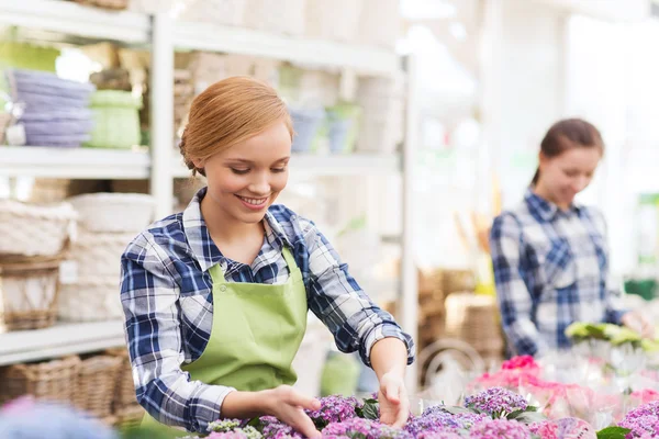 Happy woman taking care of flowers in greenhouse — Stock Photo, Image