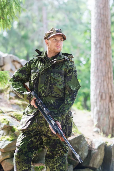 Young soldier or hunter with gun in forest — Stock Photo, Image