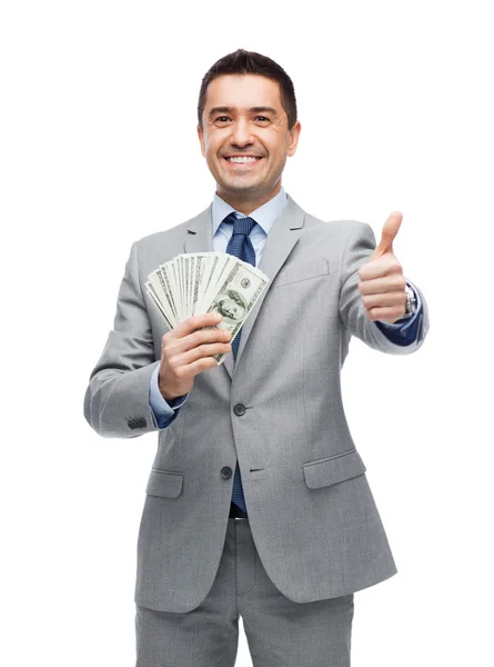 Smiling businessman with money showing thumbs up — Stock Photo, Image