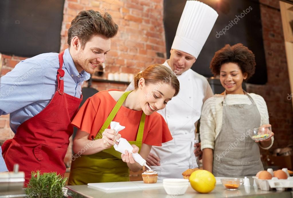 Happy friends and chef cook baking in kitchen — Stock Photo