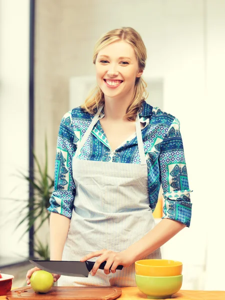 Schöne Frau in der Küche schneidet einen Apfel — Stockfoto