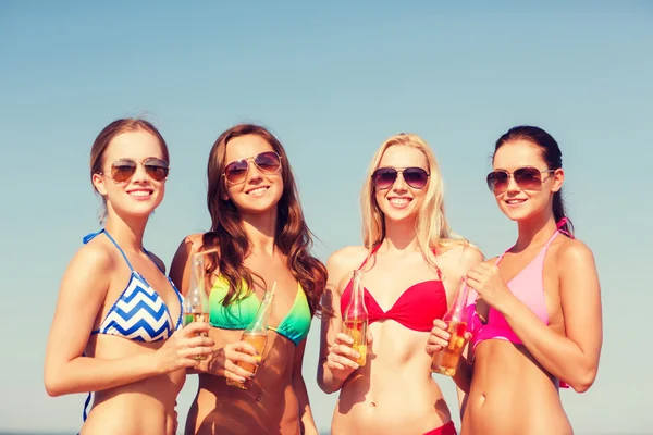 Grupo de mujeres jóvenes sonrientes bebiendo en la playa — Foto de Stock