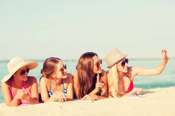 Grupo de mujeres sonrientes con teléfono inteligente en la playa — Foto de Stock