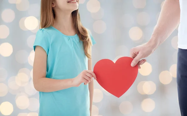 Primer plano de la niña y la mano masculina sosteniendo el corazón rojo — Foto de Stock