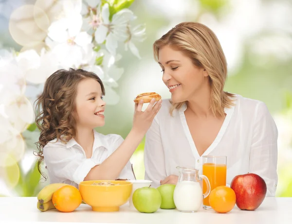 Happy mother and daughter eating breakfast — Stock Photo, Image