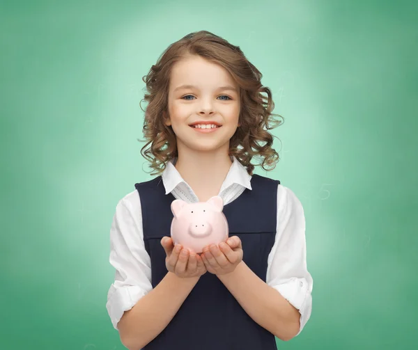 Menina feliz segurando porquinho banco em palmas — Fotografia de Stock