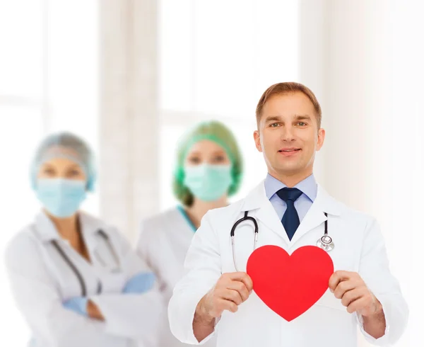 Kırmızı kalp ve stetoskop ile gülümseyen erkek doktor — Stok fotoğraf