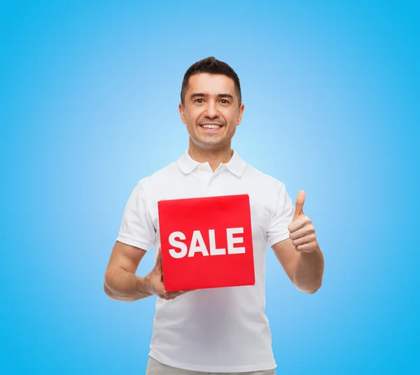 Усміхнений чоловік з червоним знаком продажу, що показує великі пальці вгору — стокове фото