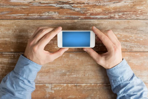 Close up van mannelijke handen met smartphone op tafel — Stockfoto