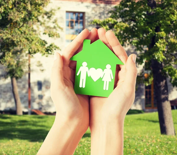 Hands holding green house with family — Stock Photo, Image