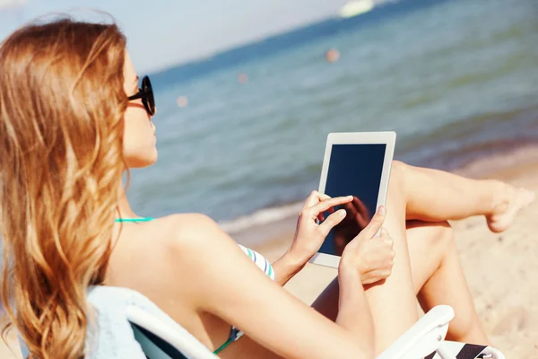 Dziewczynka, patrząc na komputer typu tablet na plaży — Zdjęcie stockowe