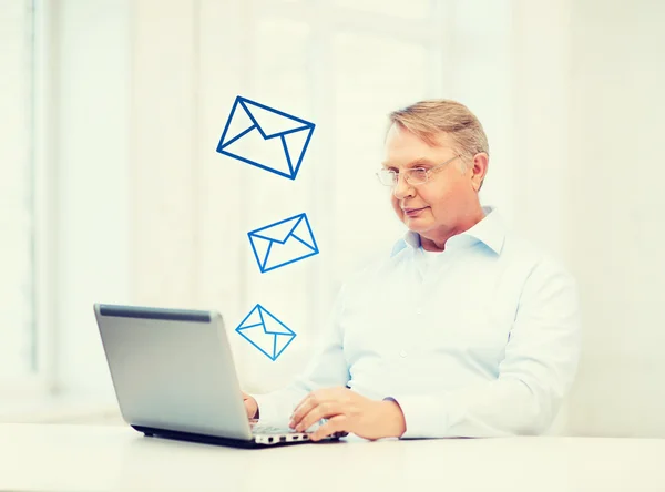 Oude man in brillen werken met laptop thuis — Stockfoto