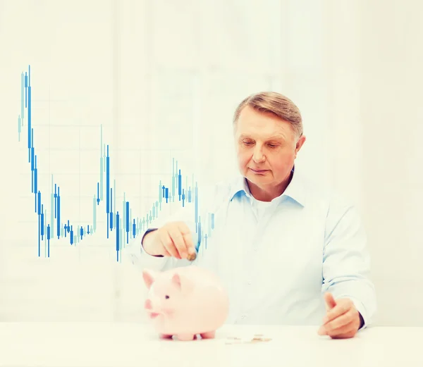 Velho colocando moeda em grande banco porquinho — Fotografia de Stock