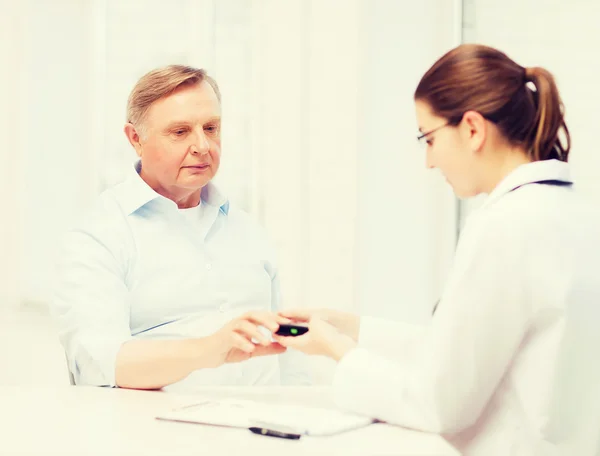 Female doctor or nurse measuring blood sugar value — Stock Photo, Image