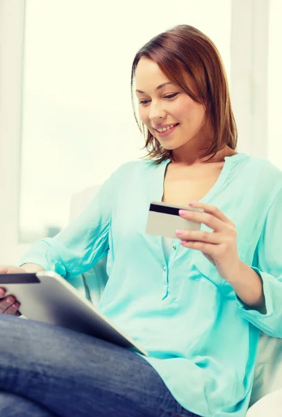 Mulher feliz com tablet pc e cartão de crédito em casa — Fotografia de Stock