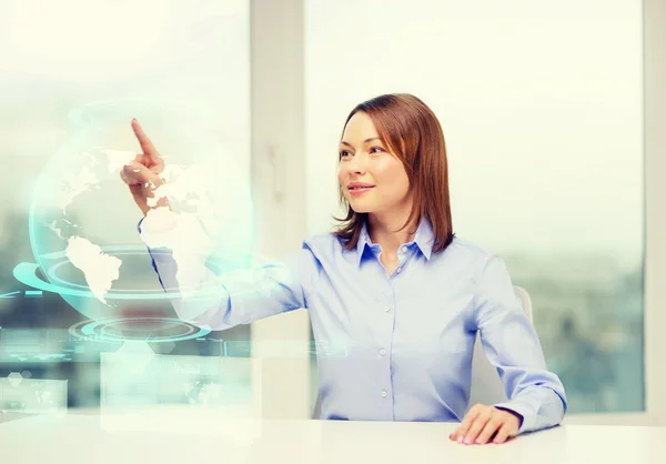 Lächelnde Frau zeigt auf das Hologramm der Erde — Stockfoto