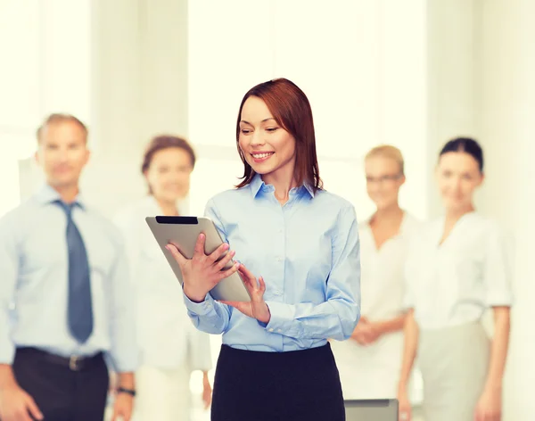 Lächelnde Frau blickt im Büro auf Tablet-PC — Stockfoto