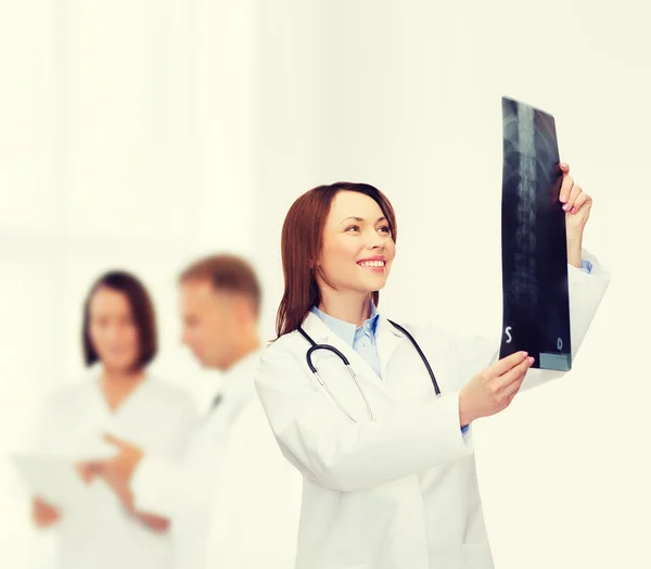 Doctora sonriente mirando rayos X — Foto de Stock