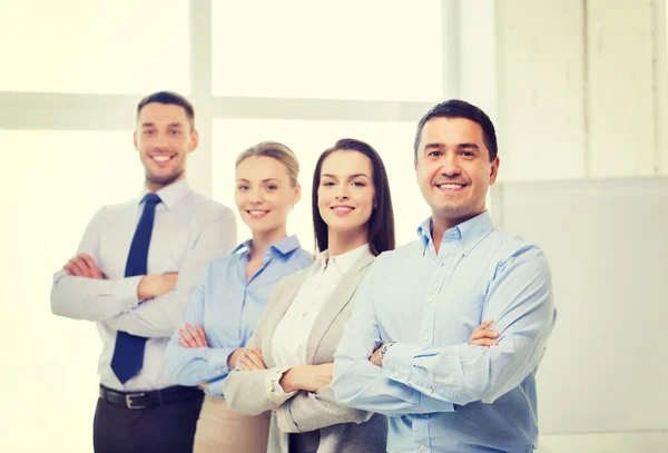 Empresário sorridente no cargo com equipe nas costas — Fotografia de Stock