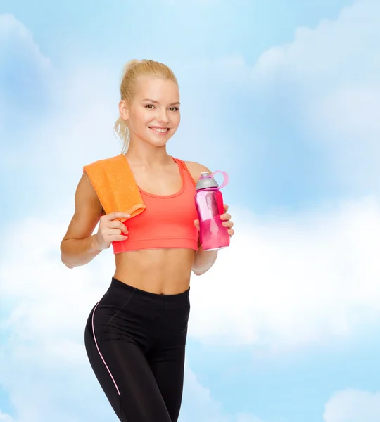Lächelnde sportliche Frau mit Wasserflasche und Handtuch — Stockfoto