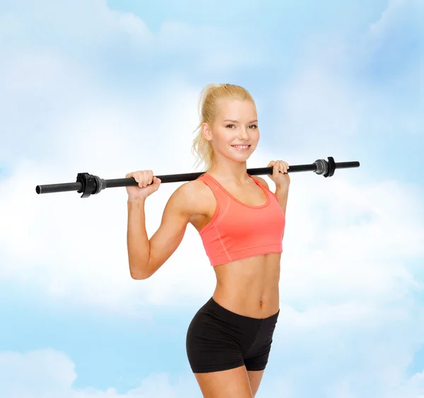 Uśmiechnięta sportowa kobieta ćwicząca ze sztangą — Zdjęcie stockowe