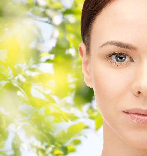 Junge Frau Gesicht über grünen Blättern Hintergrund — Stockfoto