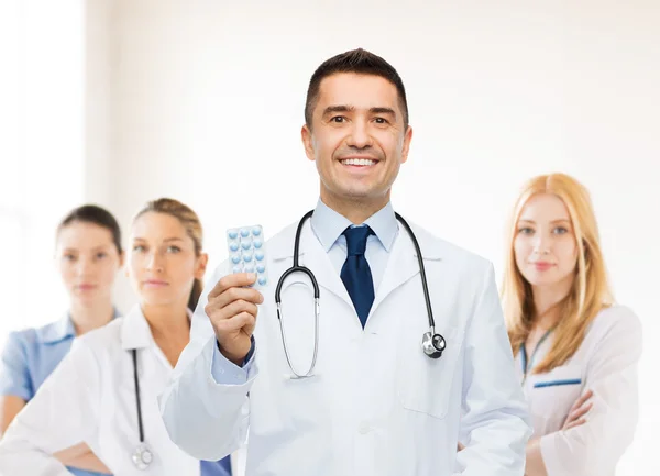 Médico do sexo masculino sorridente em casaco branco com comprimidos — Fotografia de Stock