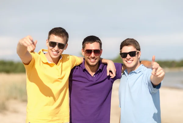 Amigos sonrientes en gafas de sol mostrando los pulgares hacia arriba — Foto de Stock