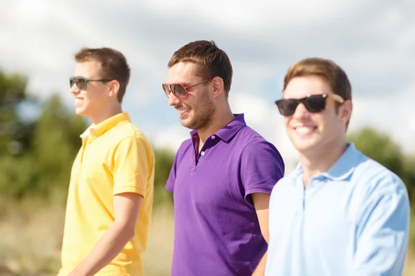 Lachende vrienden in zonnebril wandelen in de zomer — Stockfoto