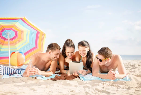Счастливые друзья с планшетным компьютером на пляже — стоковое фото