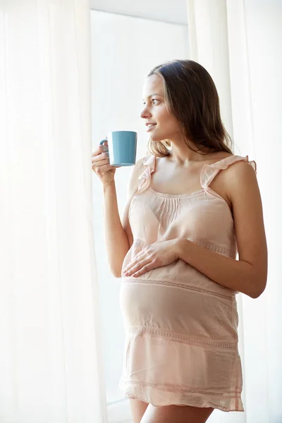 Gelukkig zwangere vrouw met kop thee drinken thuis — Stockfoto