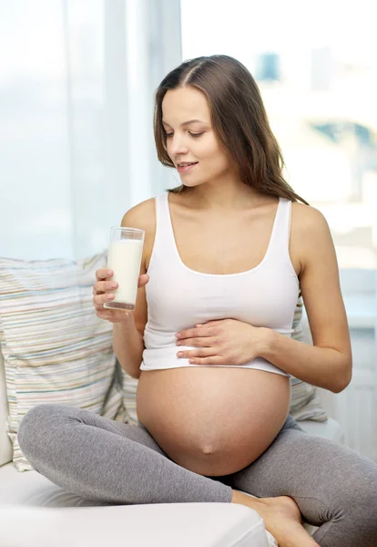 Szczęśliwa kobieta w ciąży w domu do picia mleka — Zdjęcie stockowe