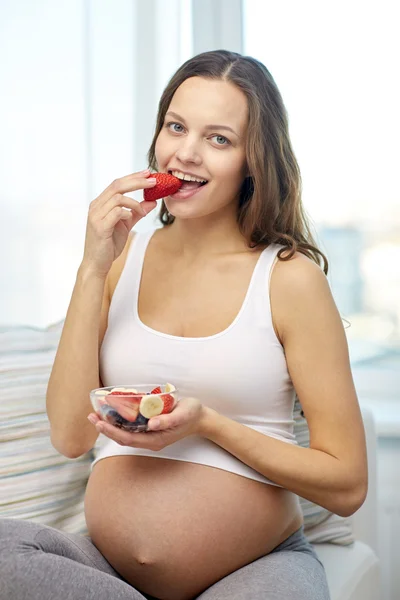 Mulher grávida feliz comer frutas em casa — Fotografia de Stock
