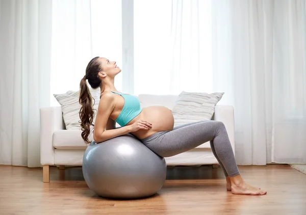 happy pregnant woman exercising on fitball at home