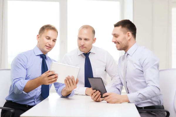 Trzy uśmiechający się biznesmenów z komputera typu tablet w biurze — Zdjęcie stockowe