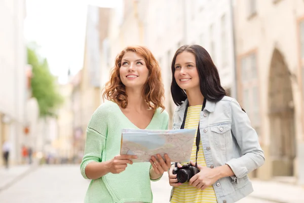 Smiling teenage girls with map and camera — Stock Photo, Image